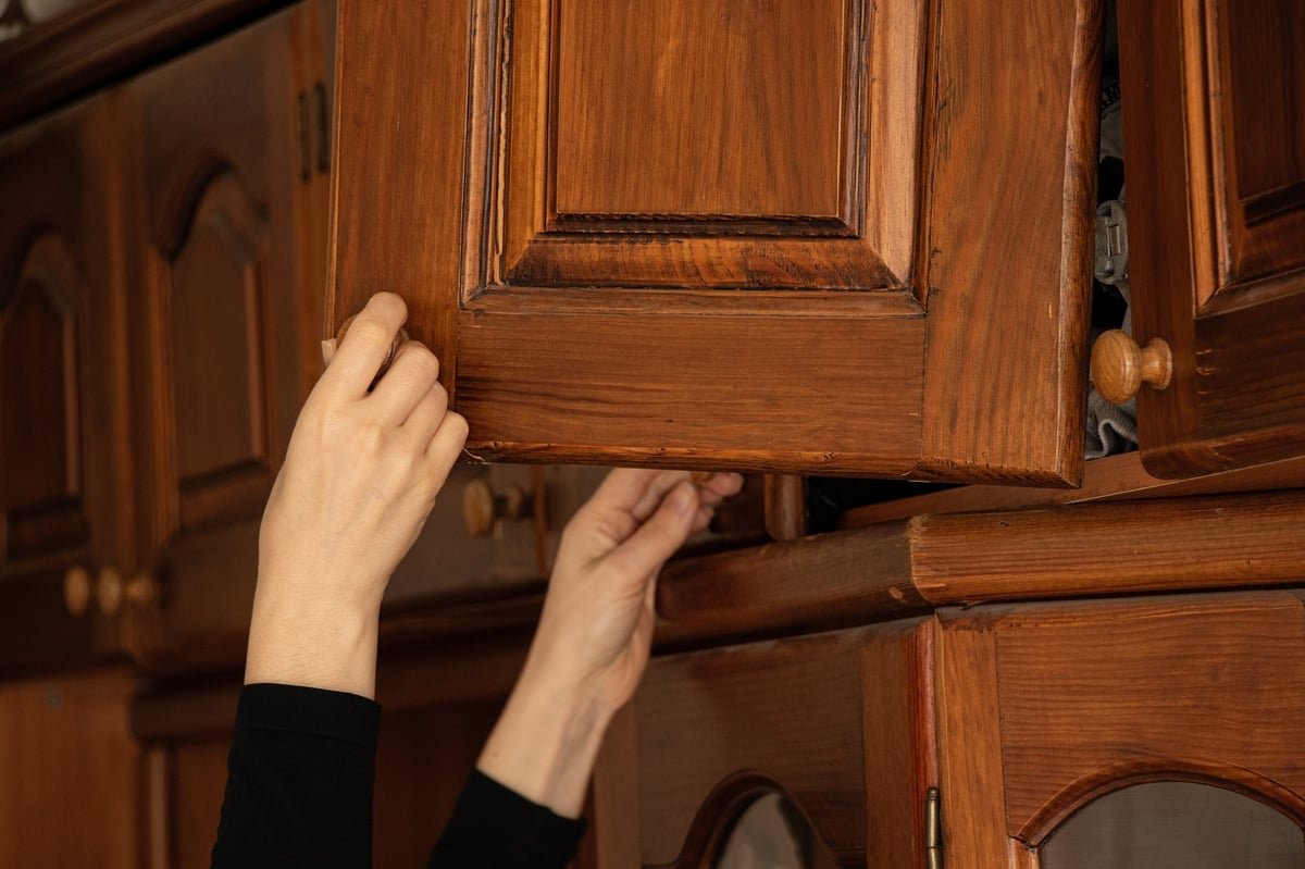Female hand opens broken door of old wooden wardrobe