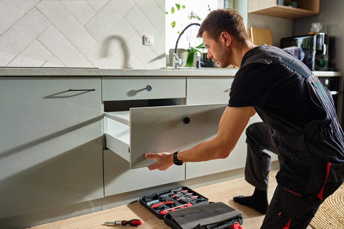 Man assembling kitchen drawer in modern cabinet