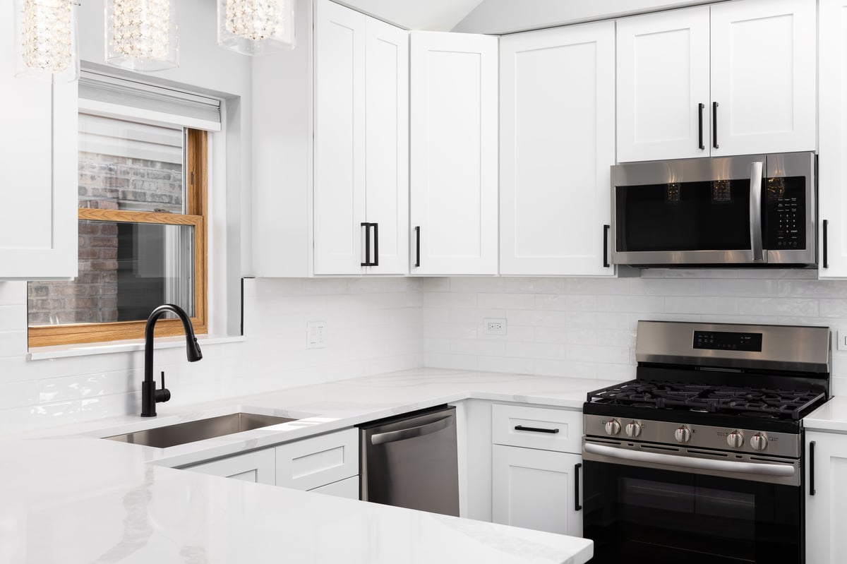 White kitchen with stainless steel appliances and marble countertop