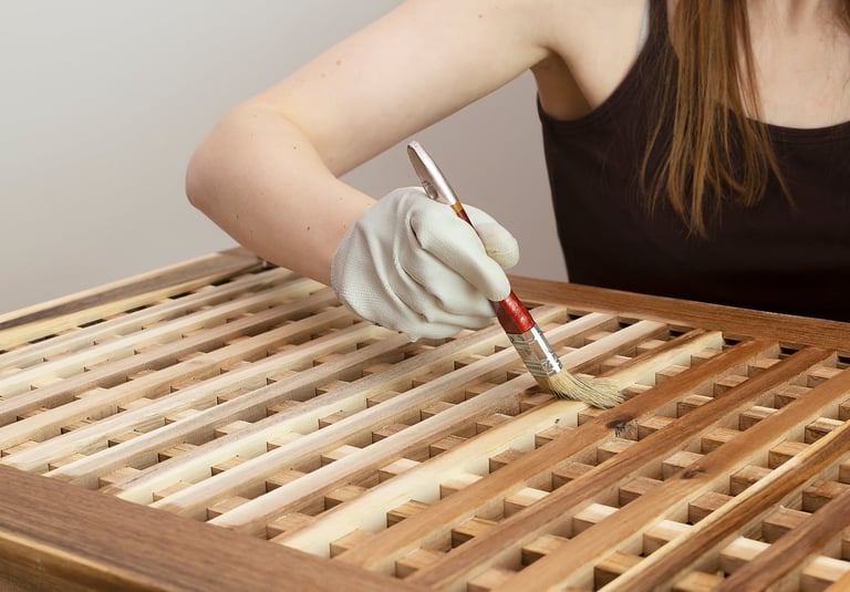 Gloved hand brushes finish onto a wooden table