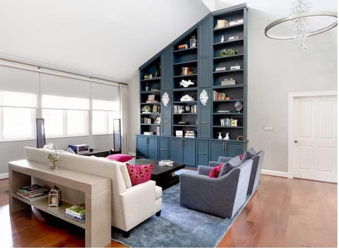 Modern living room with built-in blue shelving, beige sofa, gray armchair, and wooden coffee table