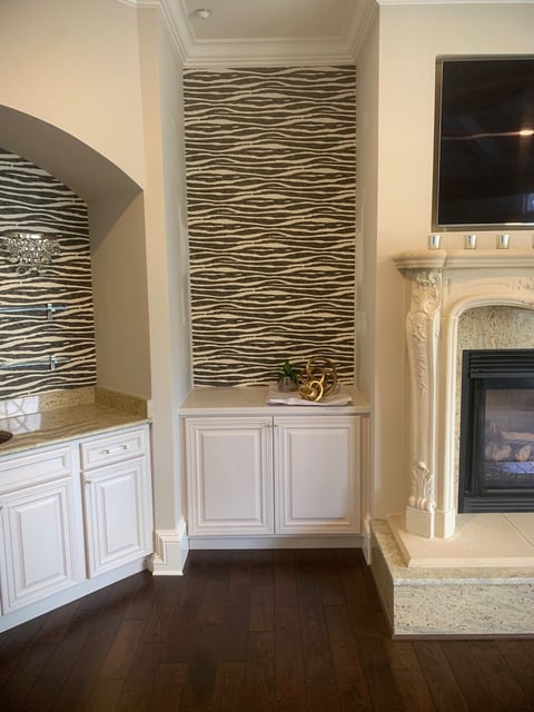 Elegant living room with striped accent walls, white cabinetry, dark wood flooring, fireplace, and mounted TV above mantel