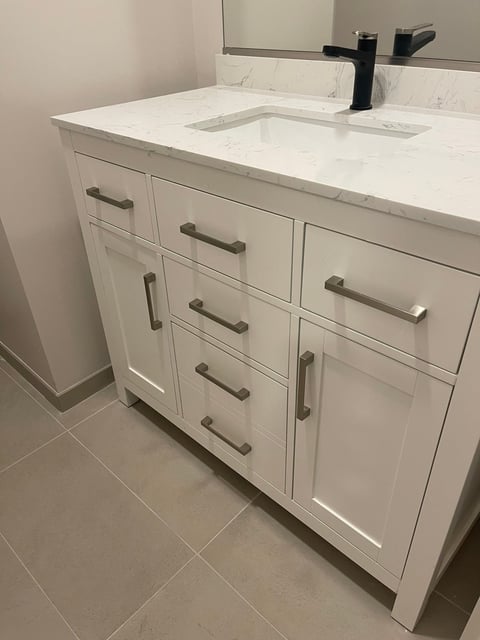 Modern white bathroom vanity with marble countertop, integrated sink, and bronze hardware and faucet